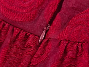 Détail de la fermeture éclair invisible sur une robe rouge foncé à relief floral