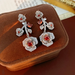 Close-up of vintage rose earrings with red stones and zircon pavé on velvet background