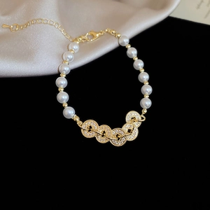 Detailed macro of pearl bracelet with zircon rings and golden clasp on satin background