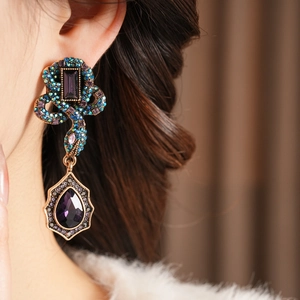 Détail de boucles d'oreilles serpent vintage avec cristaux violets et fini bronze