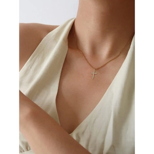 Detail of a gold-plated cross necklace with micro-pave CZ stones worn by a model