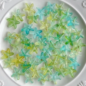 Close-up of gradient blue acrylic starfish beads with gold glitter on white plate