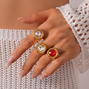 Close-up of three gold rings with large square pink, white and red zircon stones