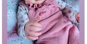 Detailed knit texture and ruffle collar of a baby pink romper with floral bodysuit