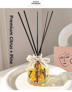 Close-up of glass diffuser with dried citrus slices and pine needles in a ceramic tray