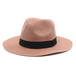Detail view of woven pink straw panama hat featuring a black ribbon band and crisp texture
