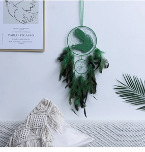 Close-up of green dinosaur dreamcatcher featuring feathers and beads in a nursery setting