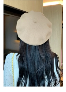 Detail view of a soft beige wool beret showing its elegant shape and warm knit texture