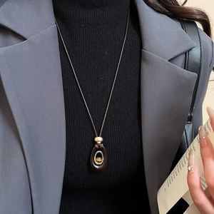 Detailed macro view of an oval resin tiger eye pendant on a long brown woven cord necklace