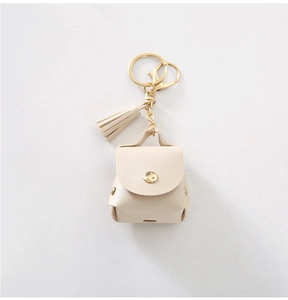 Close-up of beige PU leather mini backpack AirPods case with gold hook and tassel