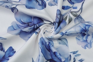 Close-up of the white fabric with blue floral print and refined twisted knot texture