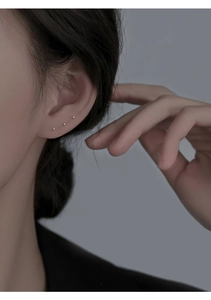Minimalist tiny sterling silver stud earrings shown on ear with three small bead designs
