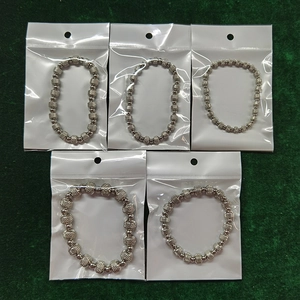 Detail of five silver beaded bracelets individually packed with white header card labels
