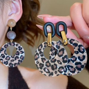 Detail of leopard print acrylic round drop earrings with gold metal rings on a model