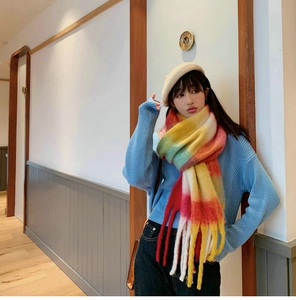 Close-up of winter rainbow striped scarf with long tassels and soft knitted texture