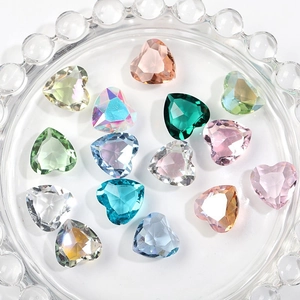 Sparkling 12mm faceted glass heart crystals in various colors on a glass plate