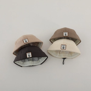 Dettaglio di quattro cappelli docker in tela per bambini in vari colori con etichetta a S