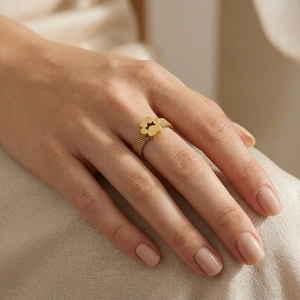 Minimalist gold mesh band ring featuring a hollow flower motif shown on a finger