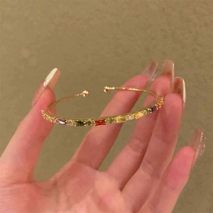 Bracciale rigido dorato con gemme arcobaleno colorate dal design moderno e stile aperto