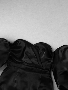 Close-up of black satin off-shoulder dress featuring puff sleeves and pleated bodice