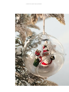 Clear glass Christmas ball ornament featuring Santa Claus figurine on snowy pine branch