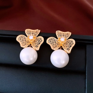 Macro shot of 18K gold plated clover earrings with hollow texture and white pearl details