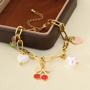 Détail d'un bracelet doré avec des breloques émaillées de cerise, fraise et perle