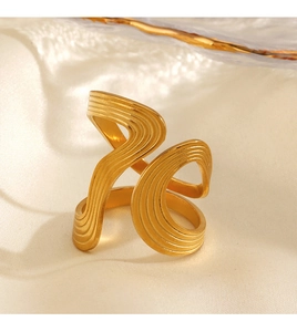 Macro detail of gold irregular wave texture open ring on beige silk background