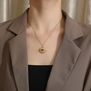 Close-up of golden solar evil eye pendant with black stone on a titanium steel chain