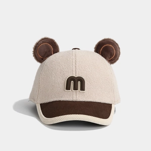 Close-up of baby winter baseball cap featuring plush teddy ears and m letter embroidery
