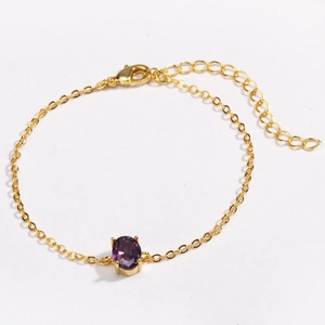 Detailed top view of gold chain bracelet featuring purple oval gemstone and lobster clasp