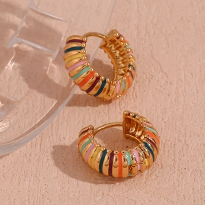 Detailed close-up of 18K gold-plated hoop earrings with colorful enamel stripes on a textured surface