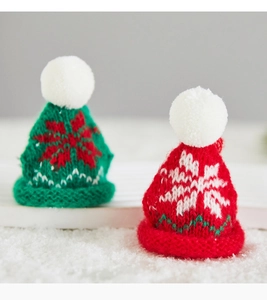 Detailed close-up of knitted mini Christmas hats with snowflake embroidery on snow