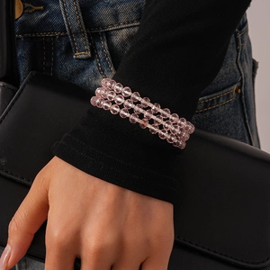 Detailed macro view of triple-layered pink faceted glass beaded wrap bracelet on wrist