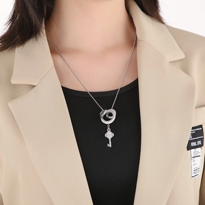 Detail view of silver key pendant with rhinestone rings on a minimalist necklace