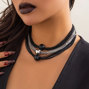 Detail of layered box chain necklace with large metallic beads on a model's neck