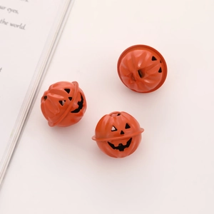 Close-up of three orange metal pumpkin bells with hollow Halloween face carvings
