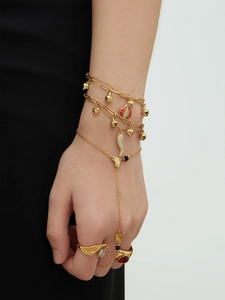 Détail d'un ensemble bracelet et bague dorés avec breloques portés sur le poignet
