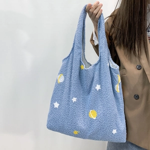 Detail of blue faux shearling tote bag featuring embroidered stars and planet patterns