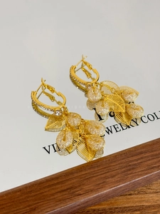 Detailed shot of vintage gold leaf earrings with teardrop pendants on mirror background