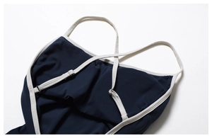 Détail des bretelles croisées et boucles en métal d'un body de yoga bleu foncé