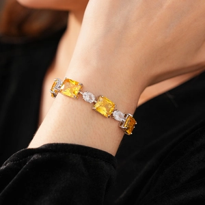 Close-up of a silver bracelet with yellow and white zircons worn on a model's wrist