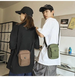 Detail shot of khaki and army green canvas messenger bags styled by models in a studio