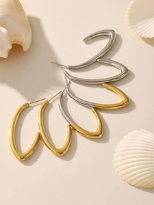 Boucles d'oreilles minimalistes en forme de C en or et argent sur un fond de coquillage