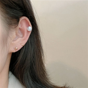 Close-up of minimalist gold hoop and irregular baroque pearl stud earring on model ear