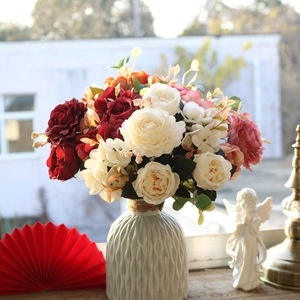 Silk red and white roses in a textured ceramic vase on a sunlit windowsill décor