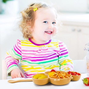 Brown silicone bee baby suction plate set with spoon and toddler in background