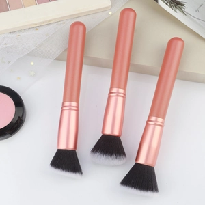 Detailed close-up of makeup brushes with matte coral handles and rose gold ferrules