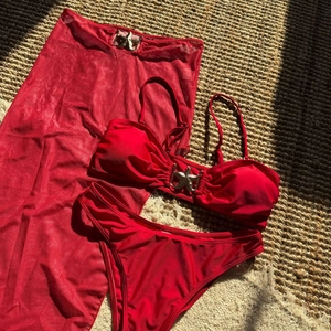 Dettaglio bikini rosso a tre pezzi con fibbia a stella marina dorata su stuoia di paglia