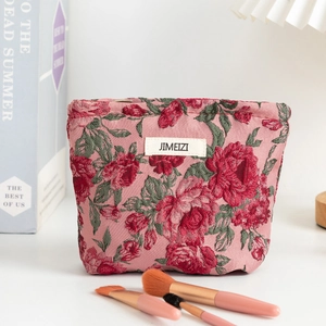 Close-up of pink jacquard makeup bag featuring red rose floral patterns and metallic zipper